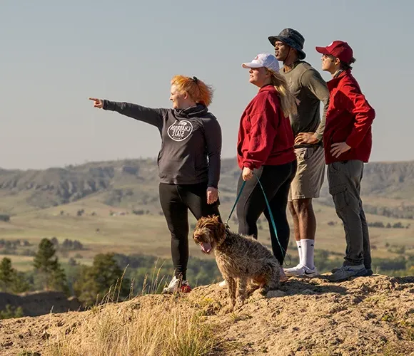 Four hikers and a dog overlooking a rugged landscape